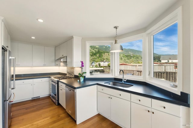 8 Rafael Patio, Stinson Beach, CA 94970 - kitchen featuring a sink, stainless steel appliances, dark countertops, light wood-style flooring, and white cabinets