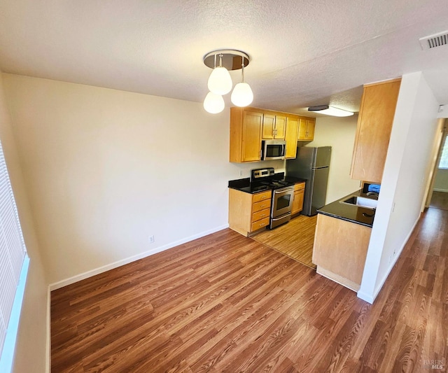 900 Cambridge Dr Unit 122, Benicia, CA 94510 - kitchen with appliances with stainless steel finishes, wood finished floors, baseboards, dark countertops, and a textured ceiling