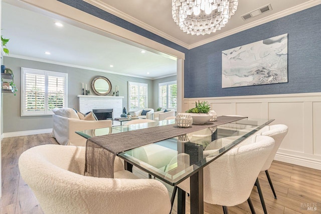 37 Angela Ave, San Anselmo, CA 94960 - dining space with a chandelier, wood finished floors, a fireplace, a wainscoted wall, and crown molding
