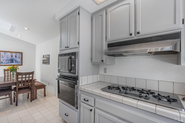 2016 Stonefield Ln, Santa Rosa, CA 95403 - kitchen featuring under cabinet range hood, stainless steel gas cooktop, tile counters, lofted ceiling, and a skylight