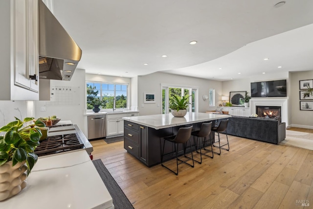 6 Live Oak Way, San Rafael, CA 94901 - kitchen with stainless steel dishwasher, island exhaust hood, white cabinets, a breakfast bar area, and light wood-style flooring
