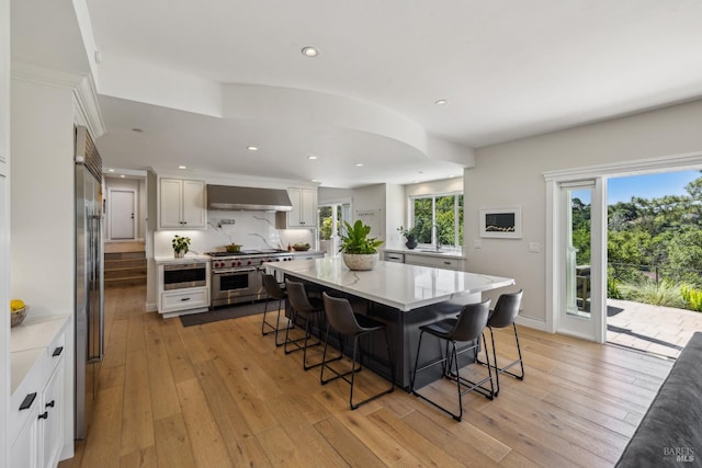 6 Live Oak Way, San Rafael, CA 94901 - kitchen featuring premium appliances, a breakfast bar, wall chimney range hood, a sink, and light wood finished floors