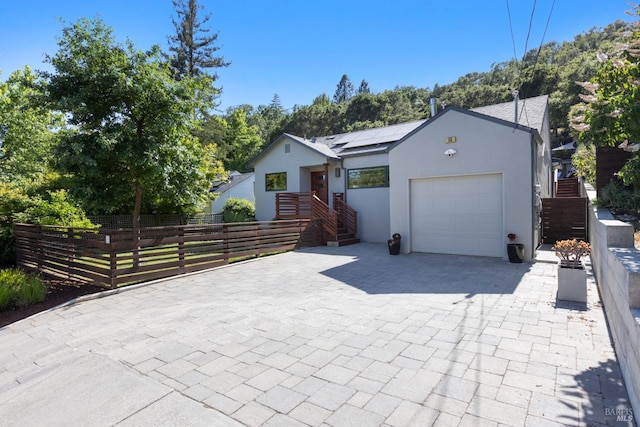 55 Durham Rd, San Anselmo, CA 94960 - view of front facade with a garage, decorative driveway, roof mounted solar panels, and stucco siding