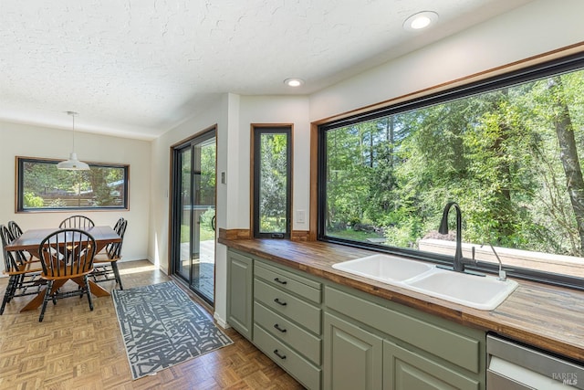 4011 Mill Creek Rd, Healdsburg, CA 95448 - kitchen featuring butcher block counters, a sink, dishwashing machine, a textured ceiling, and hanging light fixtures
