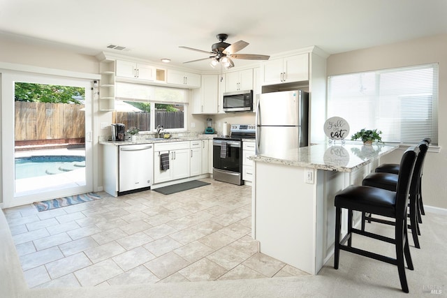481 Chelsea Way, Fairfield, CA 94533 - kitchen featuring appliances with stainless steel finishes, light stone counters, ceiling fan, white cabinetry, and a kitchen breakfast bar