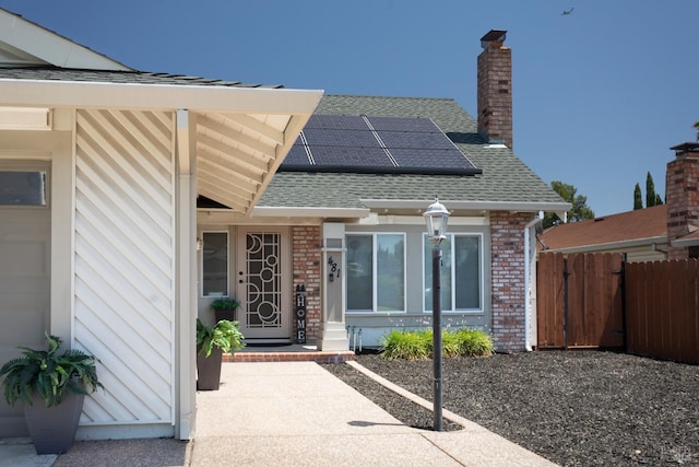481 Chelsea Way, Fairfield, CA 94533 - doorway to property featuring roof with shingles, roof mounted solar panels, a chimney, and brick siding