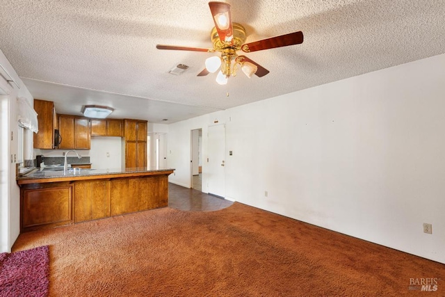 1417 Klamath Dr, Suisun City, CA 94585 - kitchen featuring brown cabinets, a peninsula, dark carpet, a textured ceiling, and ceiling fan