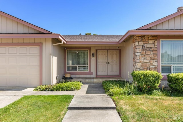 1417 Klamath Dr, Suisun City, CA 94585 - view of exterior entry featuring an attached garage, stone siding, a yard, and board and batten siding