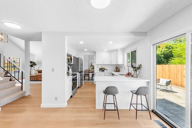 225 Riverview Dr, Vallejo, CA 94589 - kitchen featuring stainless steel appliances, a sink, light wood-style flooring, white cabinetry, and a breakfast bar area