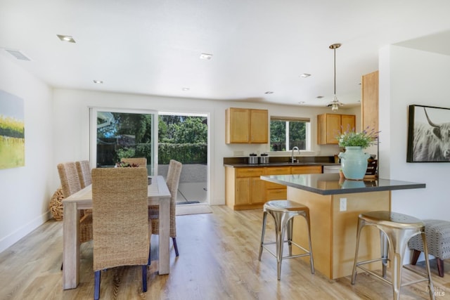 1067 Darms Ln, Napa, CA 94558 - kitchen with dark countertops, light wood-style flooring, a kitchen bar, a sink, and recessed lighting