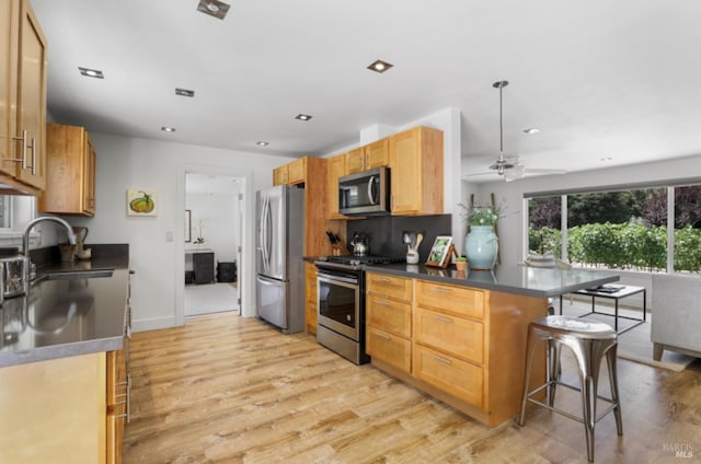 1067 Darms Ln, Napa, CA 94558 - kitchen with appliances with stainless steel finishes, a sink, dark countertops, a breakfast bar area, and light wood-style flooring