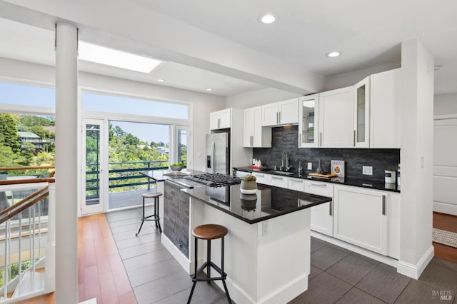 1131 W California Ave, Mill Valley, CA 94941 - kitchen with a sink, a kitchen bar, decorative backsplash, a center island, and white cabinetry