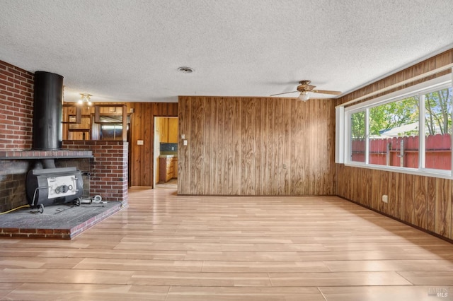 1205 Cambridge St, Novato, CA 94947 - unfurnished living room with wood finished floors, a wood stove, a ceiling fan, a textured ceiling, and wooden walls