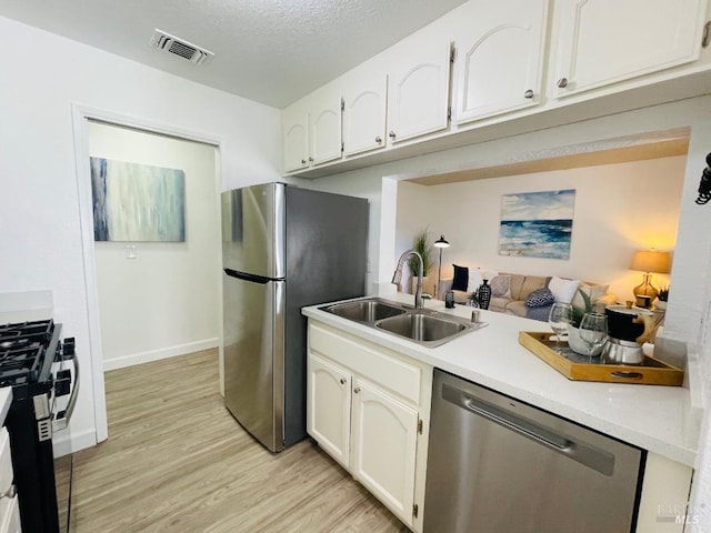 225 Pennsylvania Ave Unit B1, Fairfield, CA 94533 - kitchen featuring stainless steel appliances, a sink, light wood-style floors, light countertops, and a textured ceiling