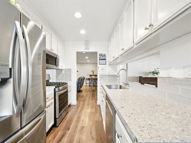 1233 Lincoln St, Fairfield, CA 94533 - kitchen featuring appliances with stainless steel finishes, a sink, light wood-type flooring, tasteful backsplash, and white cabinets