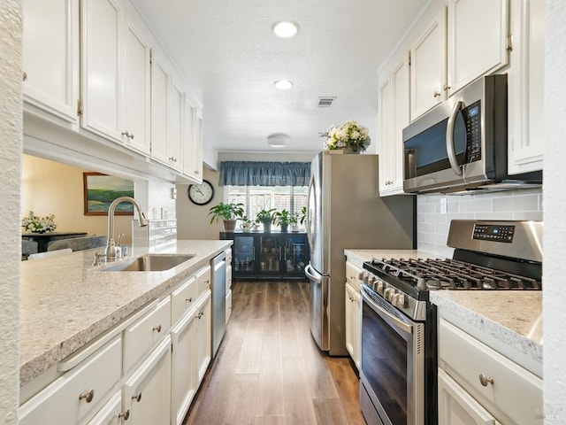 1233 Lincoln St, Fairfield, CA 94533 - kitchen featuring stainless steel appliances, a sink, wood finished floors, white cabinetry, and backsplash