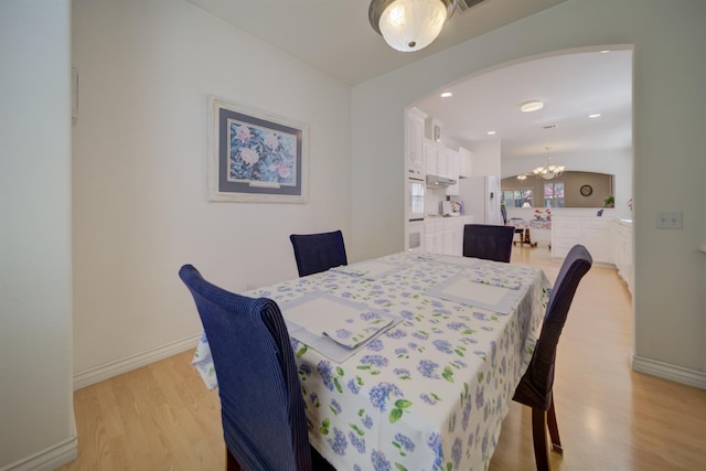 3543 Oak Shores Dr, Stockton, CA 95209 - dining space featuring a chandelier, light wood-type flooring, arched walkways, and baseboards