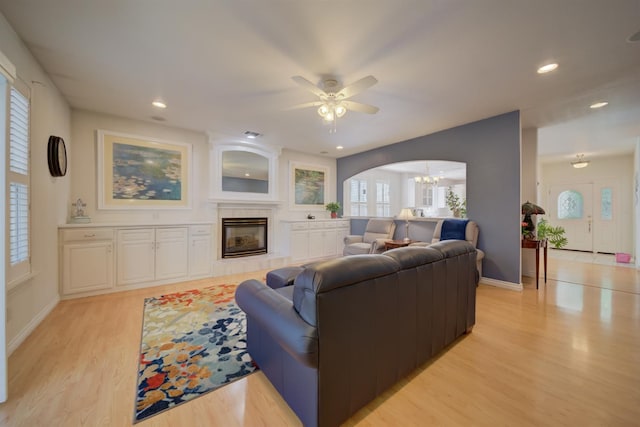 3543 Oak Shores Dr, Stockton, CA 95209 - living area with light wood finished floors, a tiled fireplace, a chandelier, ceiling fan, and baseboards