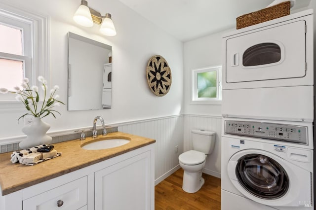 516 Howard St, Petaluma, CA 94952 - bathroom with stacked washing machine and dryer, toilet, vanity, wood finished floors, and a wainscoted wall