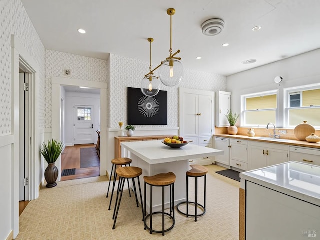 442 Piper St, Healdsburg, CA 95448 - kitchen featuring wallpapered walls, a breakfast bar area, light countertops, white cabinetry, and decorative light fixtures