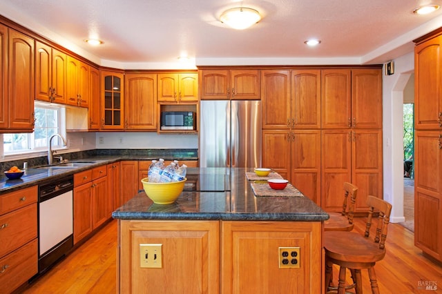 15866 Wright Dr, Guerneville, CA 95446 - kitchen with appliances with stainless steel finishes, a sink, light wood-style flooring, arched walkways, and brown cabinetry