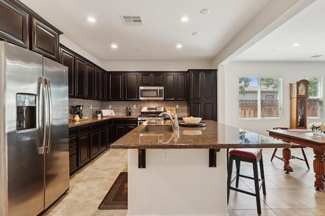 2032 Hunt St, Woodland, CA 95776 - kitchen with stainless steel appliances, a sink, dark stone countertops, a kitchen breakfast bar, and tasteful backsplash