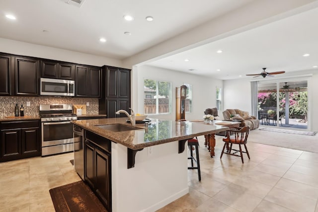2032 Hunt St, Woodland, CA 95776 - kitchen with appliances with stainless steel finishes, a sink, a kitchen breakfast bar, dark stone countertops, and a kitchen island with sink