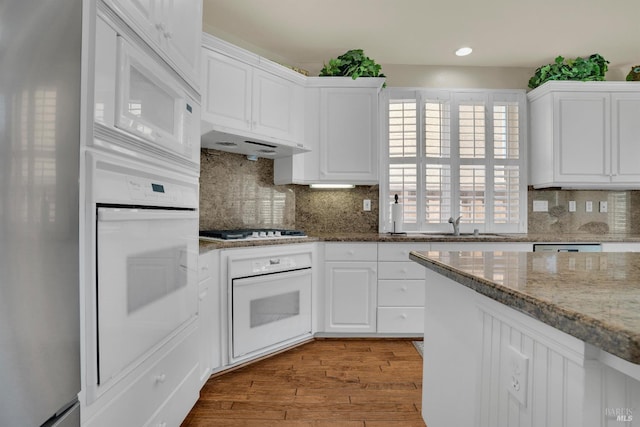 116 Birmingham Ct, Discovery Bay, CA 94505 - kitchen with white appliances, white cabinets, light wood-style floors, under cabinet range hood, and tasteful backsplash