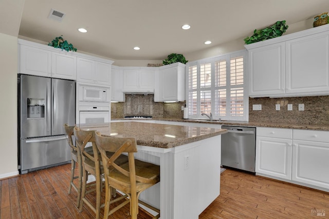 116 Birmingham Ct, Discovery Bay, CA 94505 - kitchen with appliances with stainless steel finishes, light wood-type flooring, white cabinetry, a breakfast bar area, and recessed lighting