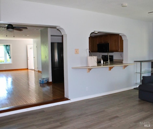 1863 Mini Dr, Vallejo, CA 94589 - kitchen with black appliances, wood finished floors, a kitchen breakfast bar, arched walkways, and a ceiling fan