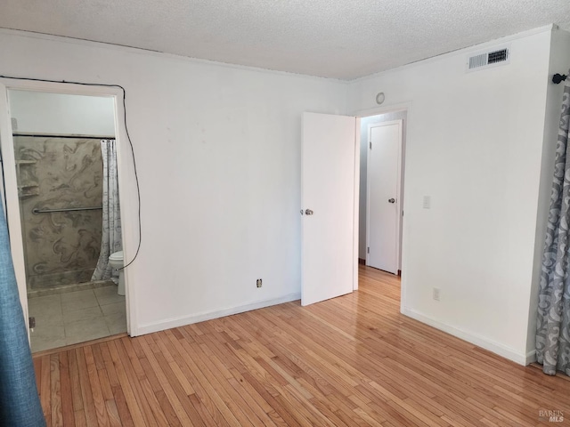 1863 Mini Dr, Vallejo, CA 94589 - unfurnished bedroom featuring light wood finished floors, a textured ceiling, connected bathroom, and baseboards