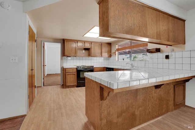 4009 Rimrock Dr, Antioch, CA 94509 - kitchen featuring black range with electric cooktop, a peninsula, light wood-style flooring, brown cabinets, and tasteful backsplash