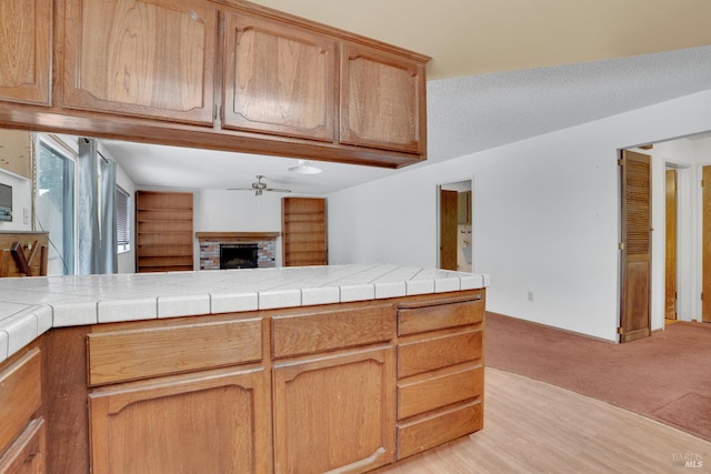 4009 Rimrock Dr, Antioch, CA 94509 - kitchen with a ceiling fan, light colored carpet, a brick fireplace, tile countertops, and open floor plan