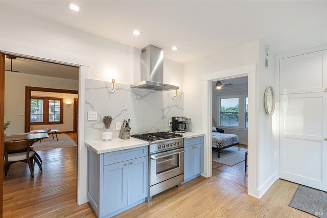 439 4th St E, Sonoma, CA 95476 - kitchen featuring stainless steel stove, wall chimney exhaust hood, light wood-style flooring, tasteful backsplash, and light stone counters