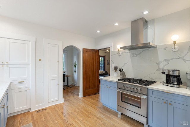 439 4th St E, Sonoma, CA 95476 - kitchen with wall chimney range hood, high end range, arched walkways, light wood finished floors, and light stone countertops