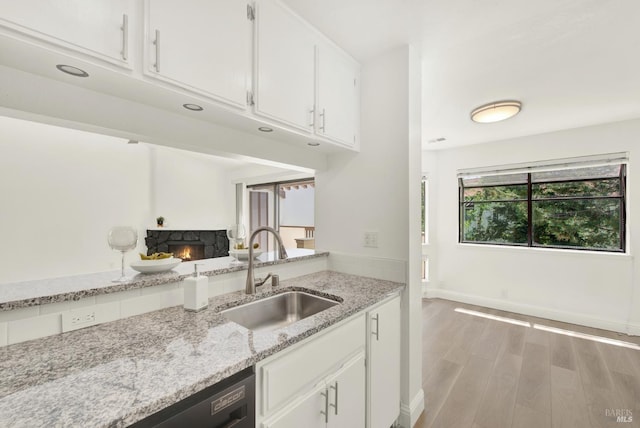 21100 Gary Dr Unit 215, Hayward, CA 94546 - kitchen featuring a sink, a fireplace, light stone countertops, white cabinets, and light wood finished floors