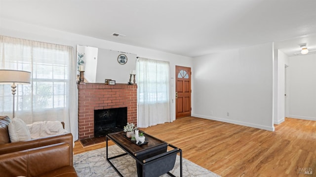 701 Nevada St, Fairfield, CA 94533 - living room featuring healthy amount of natural light, a brick fireplace, light wood-type flooring, and baseboards