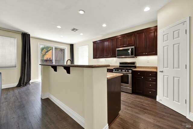 2467 Flatley Cir, Fairfield, CA 94533 - kitchen with stainless steel appliances, dark wood-type flooring, a kitchen island with sink, a kitchen bar, and recessed lighting