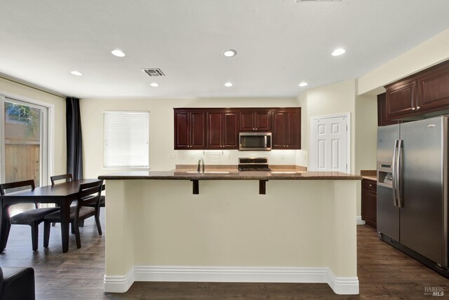 2467 Flatley Cir, Fairfield, CA 94533 - kitchen with stainless steel appliances, dark wood-style flooring, a kitchen breakfast bar, dark stone counters, and recessed lighting