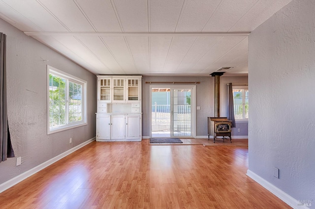 5851 Vine Hill Rd, Sebastopol, CA 95472 - unfurnished room with a textured wall, a wood stove, light wood-style flooring, and baseboards