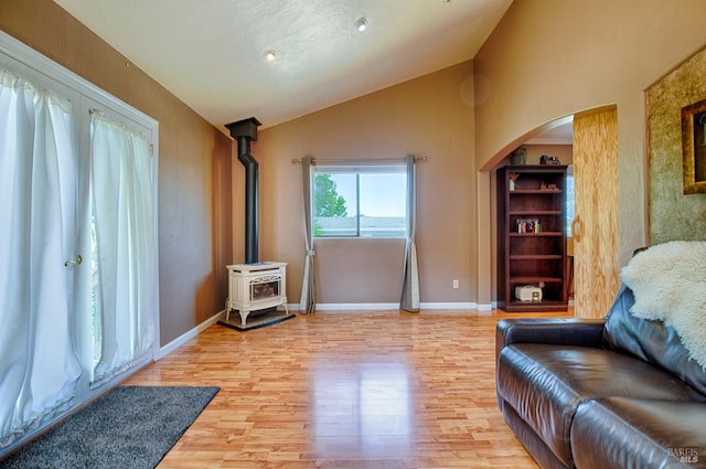5851 Vine Hill Rd, Sebastopol, CA 95472 - living room with vaulted ceiling, light wood-type flooring, arched walkways, a wood stove, and baseboards