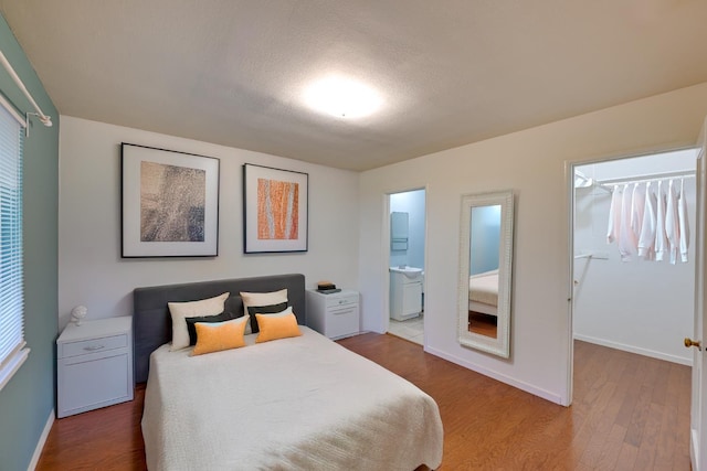110 Ruth Ct, Sacramento, CA 95819 - bedroom featuring baseboards, wood finished floors, ensuite bath, a spacious closet, and a textured ceiling