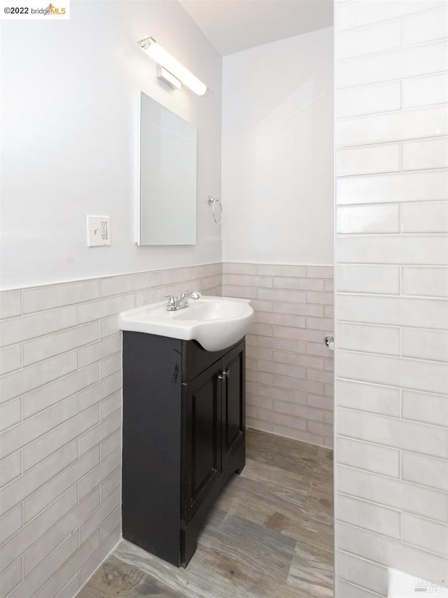 5817 Seminary Ct, Oakland, CA 94605 - bathroom featuring tile walls, vanity, wood finished floors, and a wainscoted wall