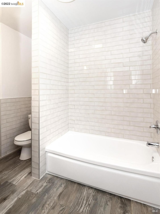 5817 Seminary Ct, Oakland, CA 94605 - bathroom featuring tile walls, toilet, wood finished floors, washtub / shower combination, and wainscoting
