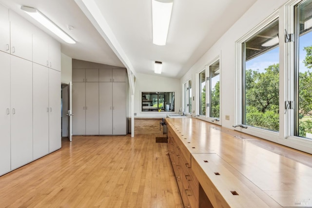 5768 Silverado Trl, Napa, CA 94558 - kitchen featuring light wood-style flooring, a sink, lofted ceiling, healthy amount of natural light, and white cabinetry