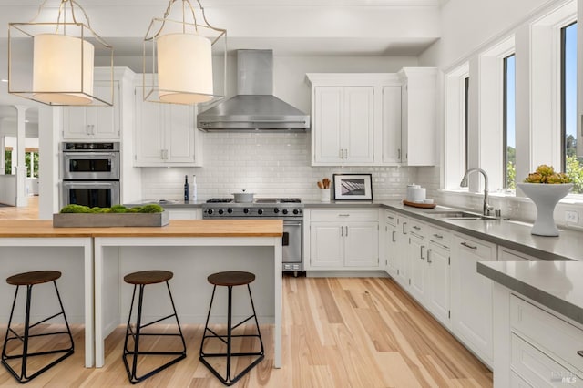 30 Sandy Ln, Mill Valley, CA 94941 - kitchen with wall chimney range hood, stainless steel appliances, wooden counters, a sink, and a kitchen breakfast bar