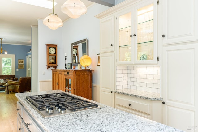 406 Franklin St, Napa, CA 94559 - kitchen featuring stainless steel gas stovetop, a wainscoted wall, glass insert cabinets, light stone countertops, and crown molding
