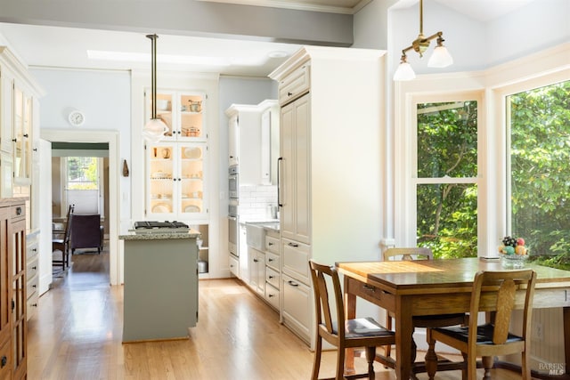 406 Franklin St, Napa, CA 94559 - kitchen featuring a kitchen island, glass insert cabinets, light wood-style flooring, backsplash, and pendant lighting