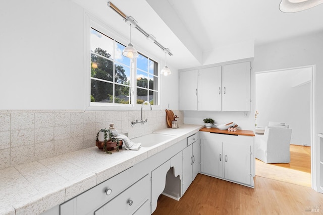 1186 E Ave, Napa, CA 94559 - kitchen featuring light wood-type flooring, a sink, decorative light fixtures, white cabinetry, and tasteful backsplash