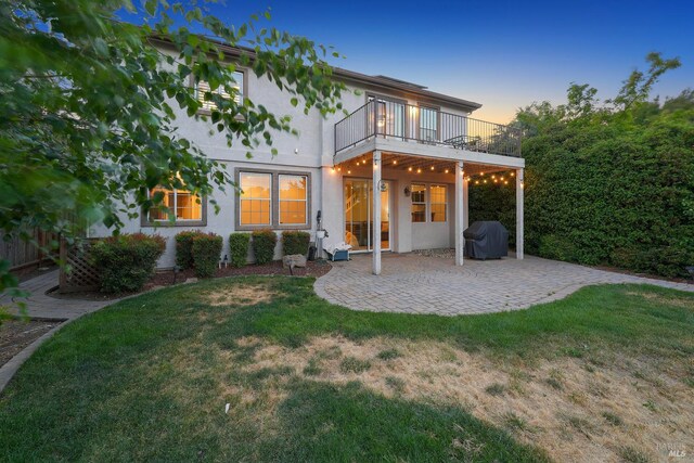 712 Tahoe Ct, Fairfield, CA 94534 - back of house at dusk featuring a balcony, a patio, a lawn, and stucco siding